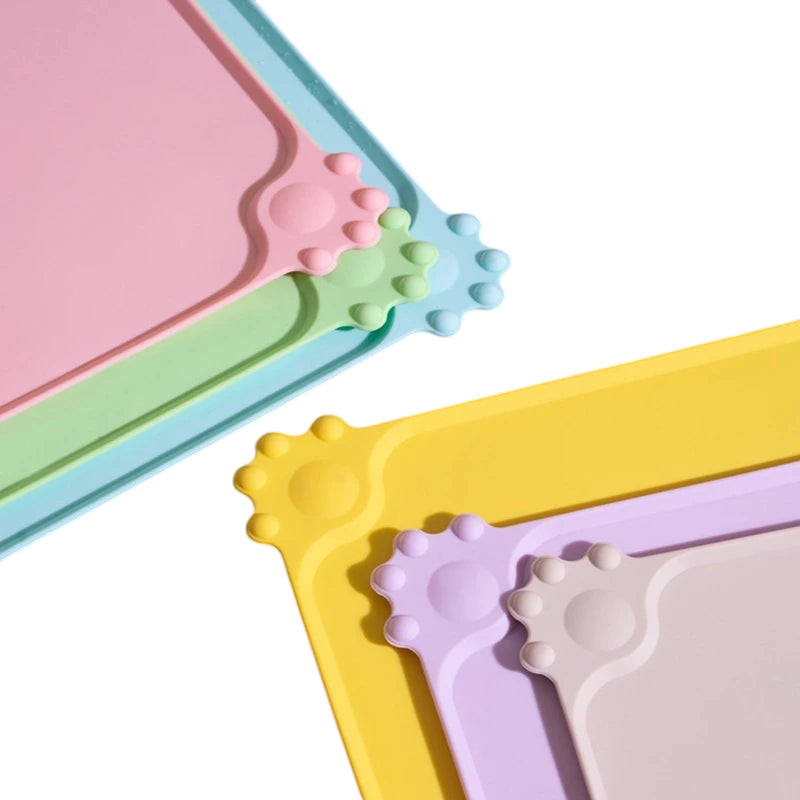 Tapis de gamelle MonPachaTech en silicone antidérapant avec motif patte, disponible en plusieurs couleurs pastel.